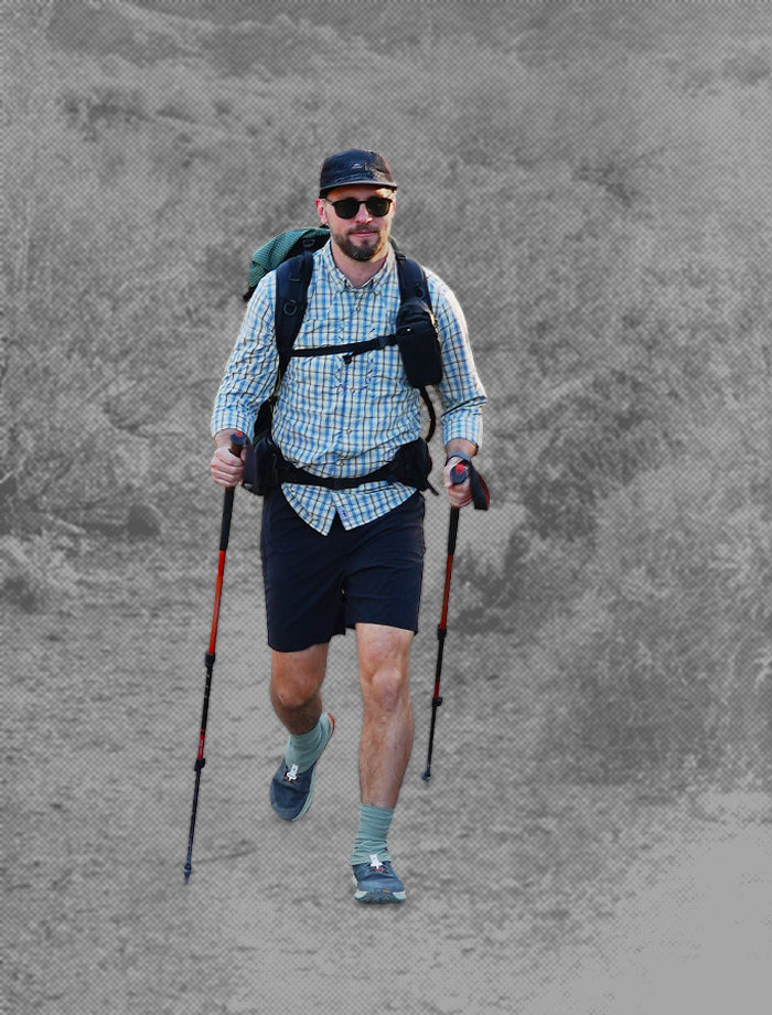 Man hiking with trekking poles and a backpack on a textured gray background