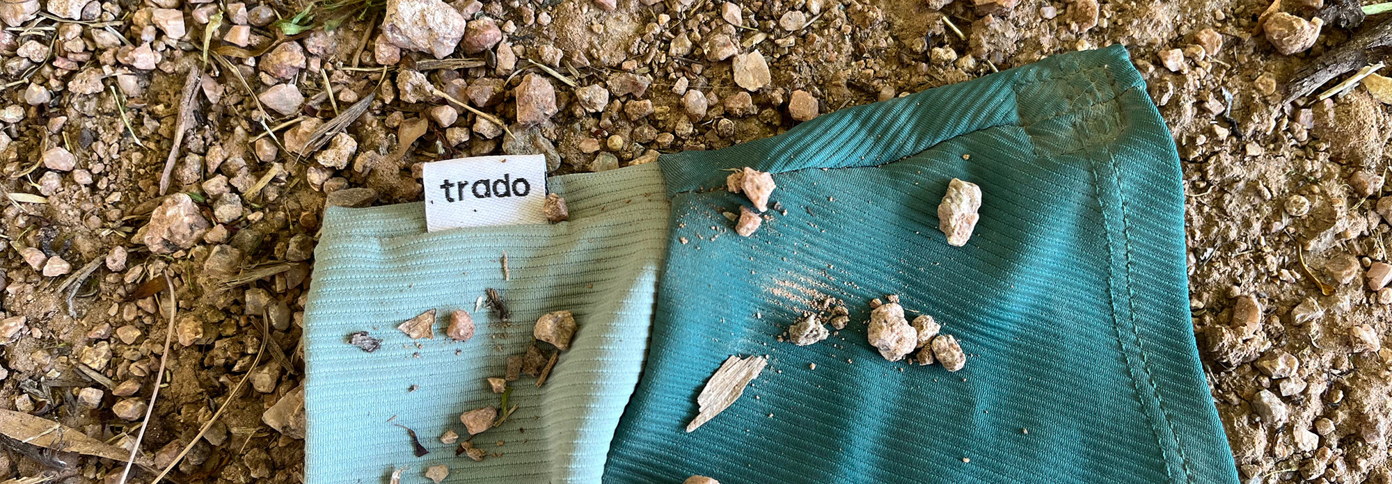gaiter with small stones on a gravel surface, featuring the brand 'trado'.