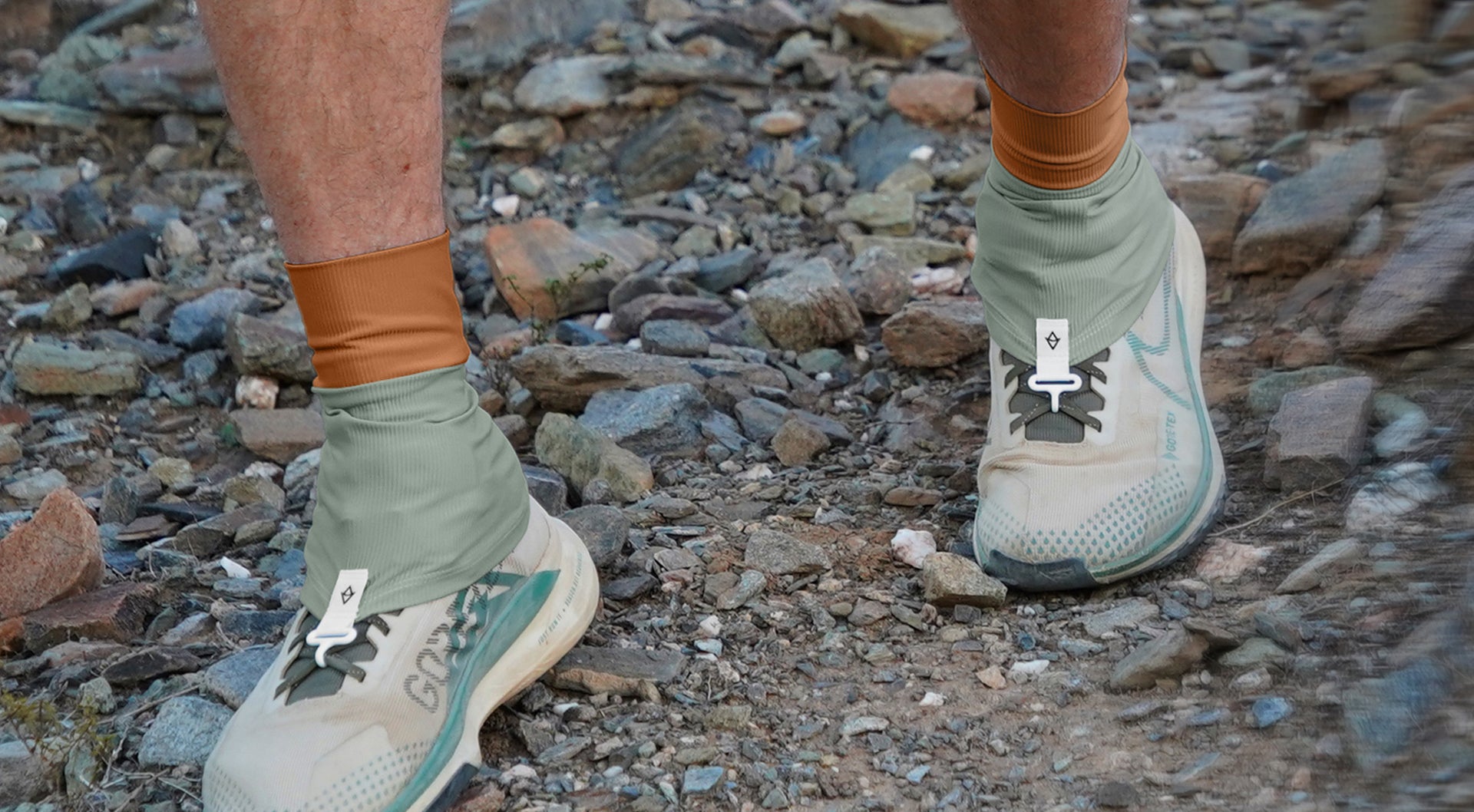 Person wearing green hiking shoes and socks on a rocky trail